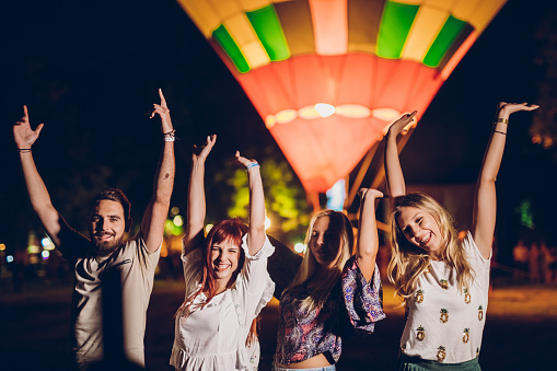 Group of friends in front of hot air balloon on a music festival