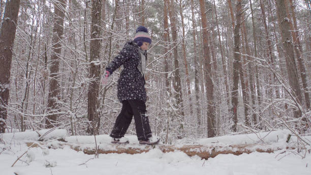 istock Girl walking on a fallen tree in winte 1049505802