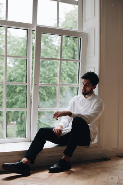 istock Man Sitting On Window Sill At Home 1049506384