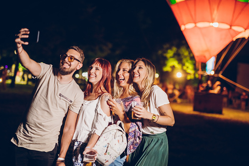 Group of friends taking selfie in front of a hot air balloon on a music festival