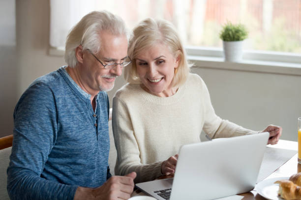istock Happy older family couple talking using laptop having breakfast together 1049512574