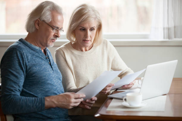 grave coppia senior preoccupata che legge documenti calcolo bollette da pagare - retirement senior adult finance couple foto e immagini stock