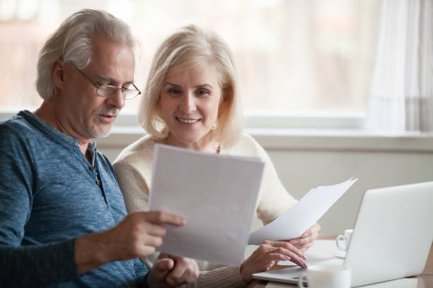 feliz mayor de edad explotación par leer buenas noticias en el documento - pension retirement planning savings fotografías e imágenes de stock
