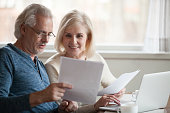 Happy older aged couple holding reading good news in document
