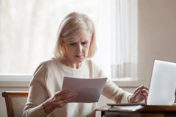 sérieuse frustrée moyenne femme âgée troublée avec des factures domestiques - utility payments photos et images de collection