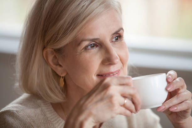 istock Thoughtful smiling middle aged woman looking away dreaming drinking coffee 1049512640