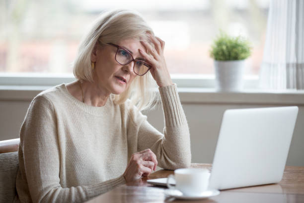 zdezorientowana dojrzała kobieta myśląca o problemie online patrząc na laptopa - old senior adult women tired zdjęcia i obrazy z banku zdjęć