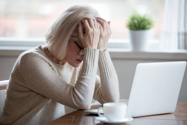 Middle-aged woman in front of laptop frustrated by bad news Upset depressed mature middle aged woman in panic holding head in hands in front of laptop frustrated by bad news, online problem or being fired by email feeling desperate shocked exhausted concept money cry stock pictures, royalty-free photos & images