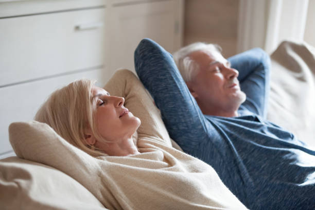 lugn äldre par avkopplande soffan att ha dagtid nap tillsammans - stressad äldre man bildbanksfoton och bilder
