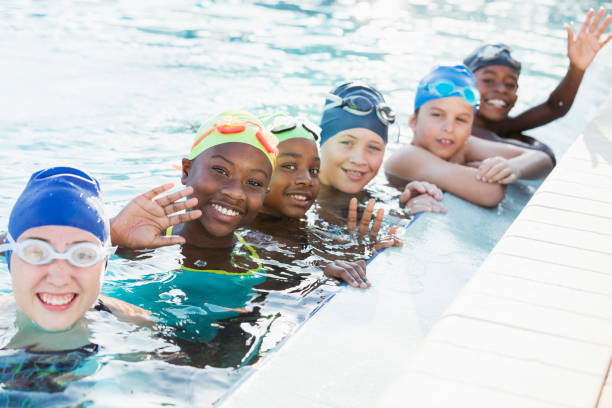 istock Multi-ethnic children on swim team in pool, waving 1049513128