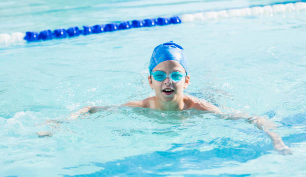 istock Boy with swim cap and goggles swimming in pool 1049513188