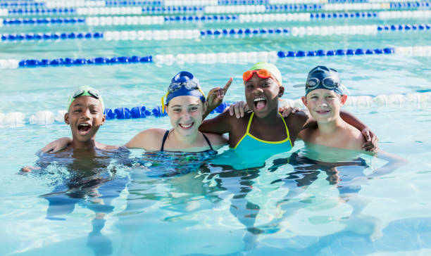 istock Multi-ethnic children in swimming pool smiling at camera 1049513480