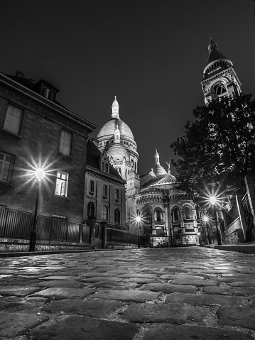 The early eving glow from street lamps on a cobbled street near to ther basilica of Sacre Couer in Montmartre district of Paris