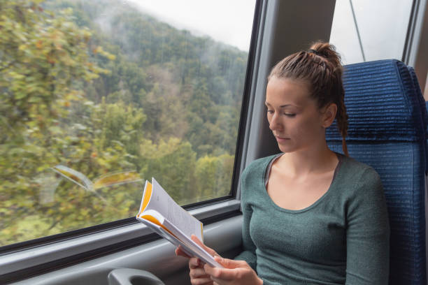 istock young cute woman reading a book while travelling by train 1049516994