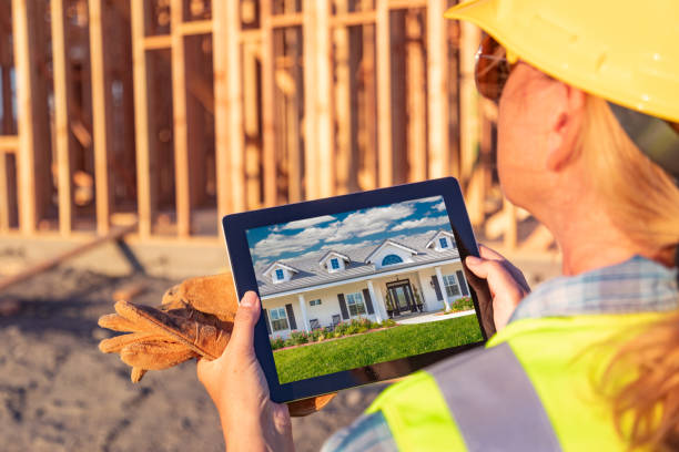 istock Female Construction Worker Reviewing House Photo on Computer Pad at Construction Site 1049517120