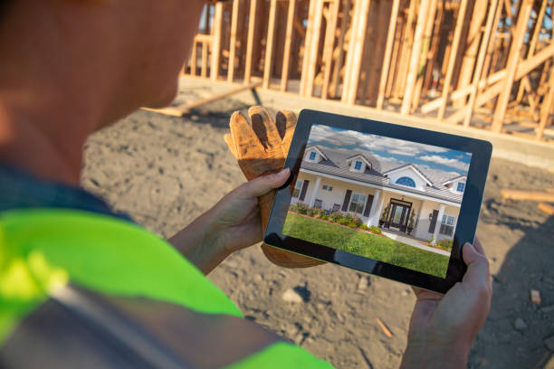 istock Female Construction Worker Reviewing House Photo on Computer Pad at Construction Site 1049517126
