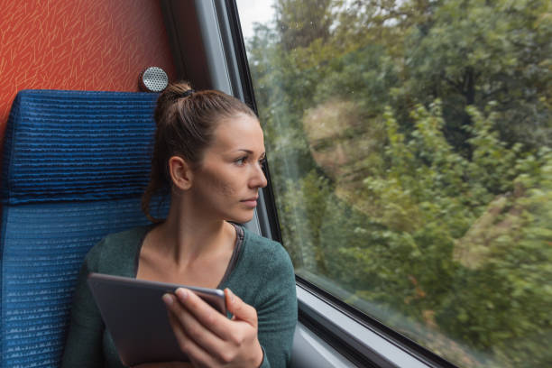 istock Young woman looking out of the window and using a tablet for studying while travelling by train 1049517246