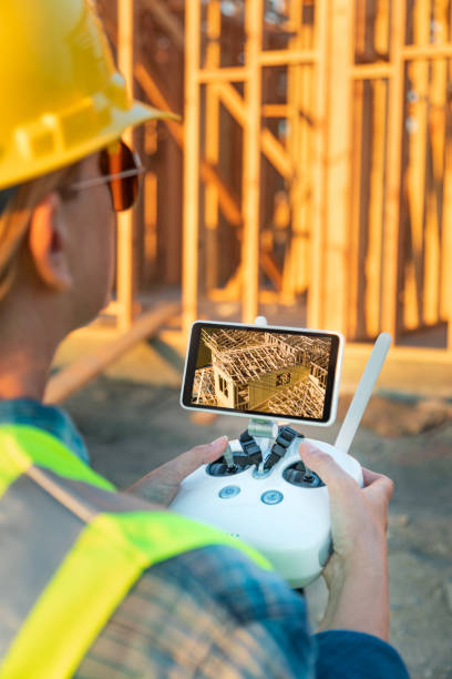 istock Female Unmanned Aircraft System (UAV) Quadcopter Drone Pilot with Controller Inspecting New House Framing 1049519516