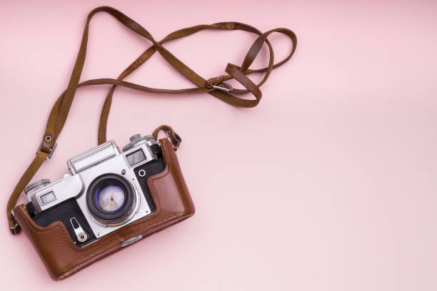 istock Old analog retro camera on pink background. Education photography courses back to school concept abstract  wallpaper. Close up, top view, copy space. 1049526428
