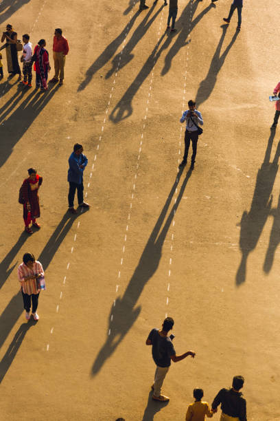 Shimla, India - June 2 2018: Tourists take a walk at Shimla Mall road during sunset. Golden hour magic. Light and shadow contrast. Aerial image of indian hill station. Crowds of Indians on vacation
