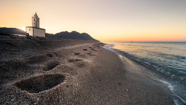 Footprints in the sand of Las Salinas Beach Sunrise on the beach of Las Salinas of the Cabo de Gata - Nijar Natural Park, in Almería (Spain). Image in which one of the most photographed buildings in Almeria appears, the Church of Las Salinas. cabo de gata photos stock pictures, royalty-free photos & images