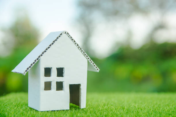 istock Eco house concept : Cardboard cut house on green grass with copy space 1049548818