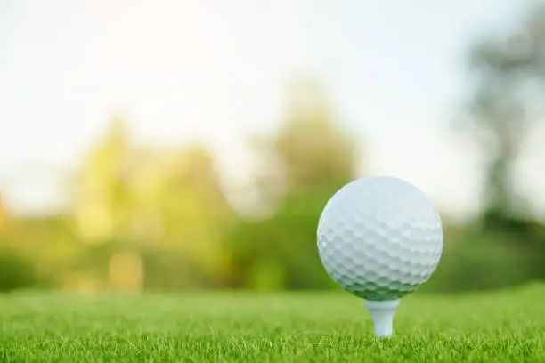 Golf ball with white tee on green grass ready to play at golf course. with copy space