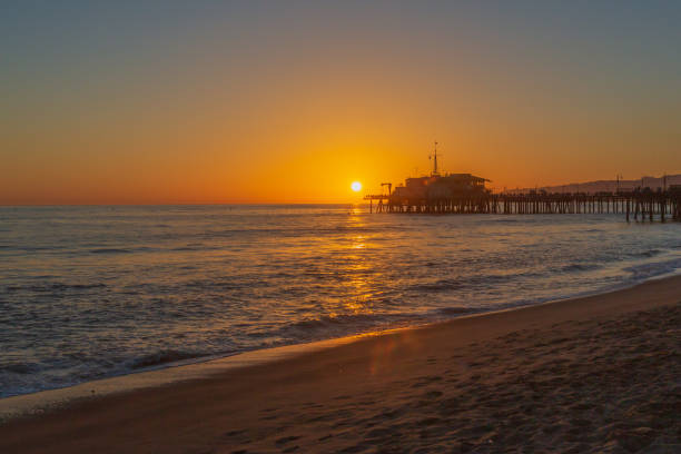 sunset over santa monica pier and beach - santa monica beach beach california wave imagens e fotografias de stock