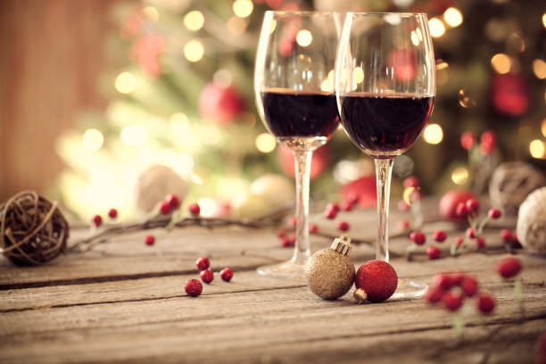 Christmas holiday red wine on a rustic wooden table in front of a Christmas tree. Very shallow depth
