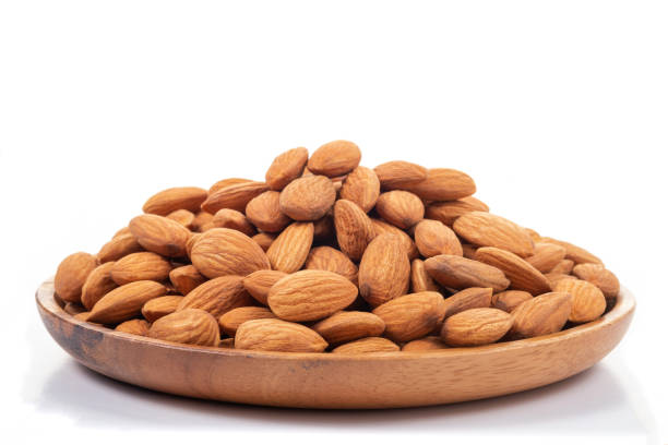 istock Almonds in wooden dish on white background. 1049560210