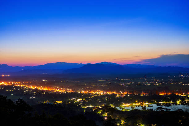 istock Aerial view at Doi Khao Kwai during blue zone after sunset. Mountain range as background with light tail on main road at Chiangrai city and big pond as foreground 1049576344