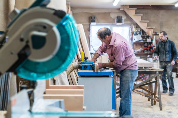 der senior 60 jahre alten mann, tischler und sashman, handwerker, arbeiten mit der industriellen fräsmaschine bei der kleinen holz-fabrik - 60 65 years stock-fotos und bilder