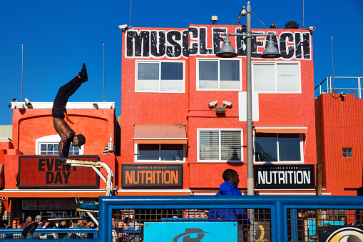 Venice Beach, Los Angeles, California - February 25 2018: Man training figures in front of orange muscle beach building