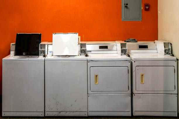 old coin laundry washing and drying machines with orange wall background