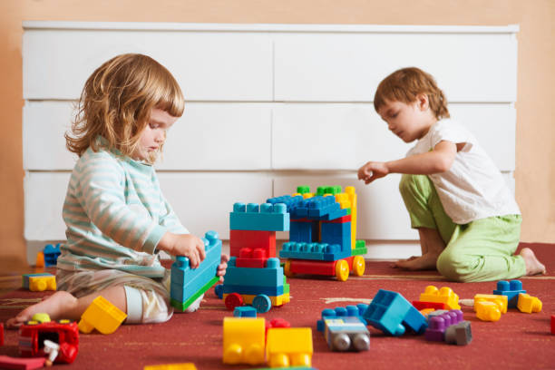 istock Two children  playing with lots of colorful plastic blocks constructor sitting on a floor indoor. 1049579286