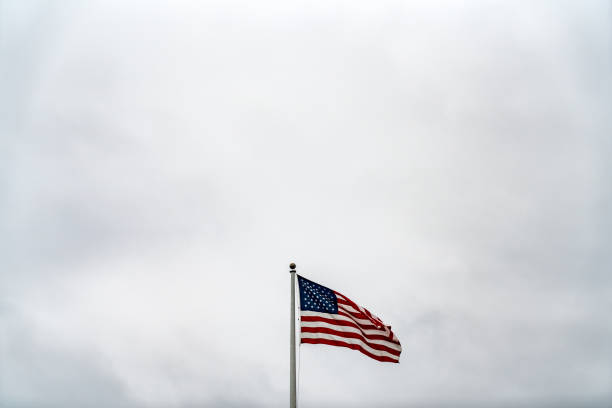 istock American flag waving on cloudy gray background 1049579316