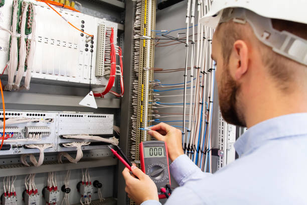 istock Engineer electrician with multimeter in electrical control box tests equipment. Maintenance of electrical panel. Worker in helmet in power supply cabinet. Service man is testing automation fuse box 1049592648
