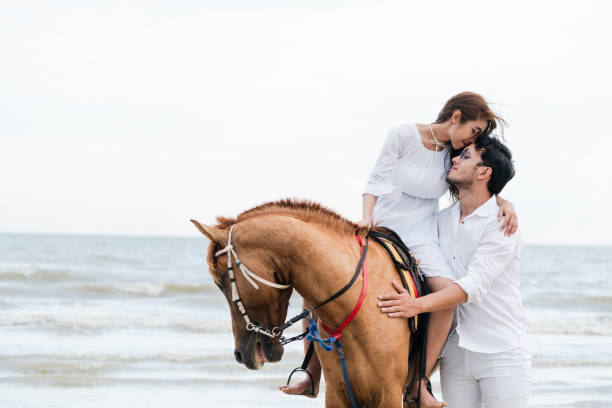 istock Young couple goes horse riding on tropical beach. 1049595772