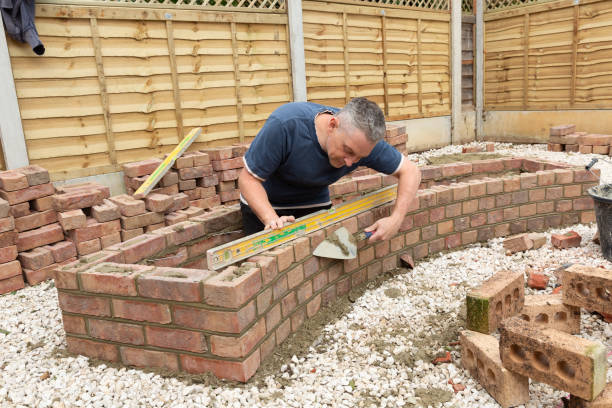 istock construction man laying and cementing clay bricks making a garden seat 1049598154