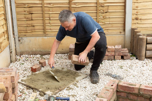istock construction man laying and cementing clay bricks making a garden seat 1049598196