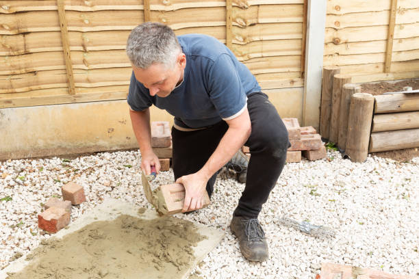 istock construction man laying and cementing clay bricks making a garden seat 1049598212