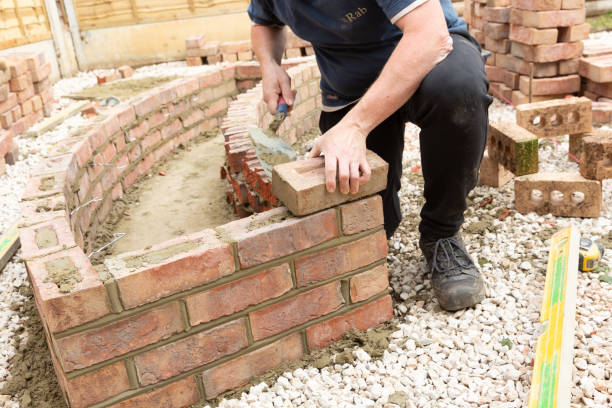 istock construction man laying and cementing clay bricks making a garden seat 1049598266