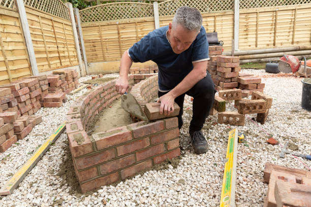 istock construction man laying and cementing clay bricks making a garden seat 1049598276
