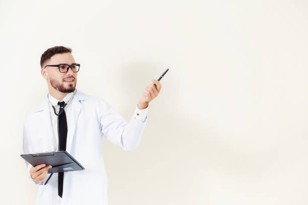 istock Male doctor points pen at empty wall copy space. 1049598750