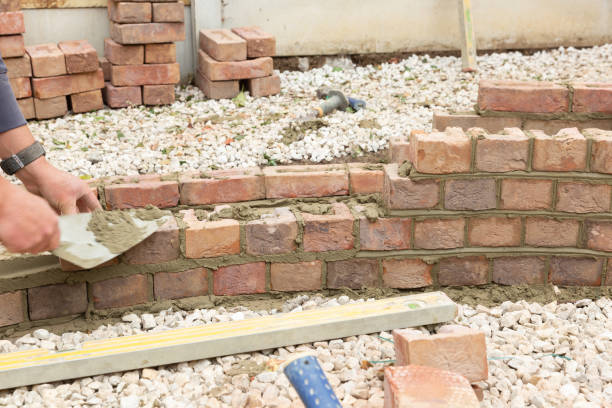 istock laying clay bricks with fresh wet cement to make a garden seat construction 1049598870