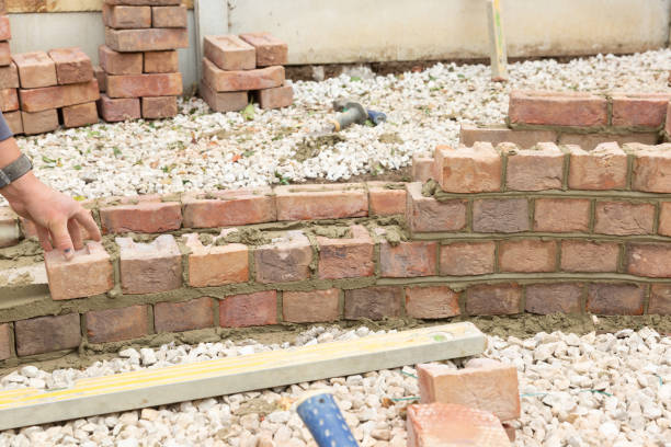 istock laying clay bricks with fresh wet cement to make a garden seat construction 1049598872