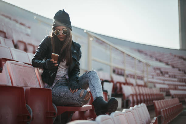 istock Casual dressed woman using phone outdoors on a sunny day at the stadium 1049609938