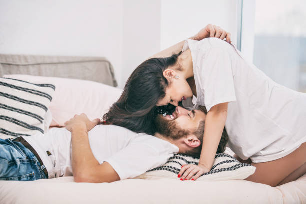 young beautiful and happy couple man and woman at home in bedroom in bed romantic and in love - romance sensuality couple bed imagens e fotografias de stock