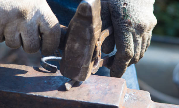 istock blacksmith performs the forging of hot glowing metal on the anvil 1049637414