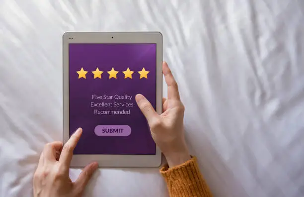 Photo of Customer Experience Concept. Happy Client Using Tablet on Bed to Writing Positive Review and Sending Feedback Online